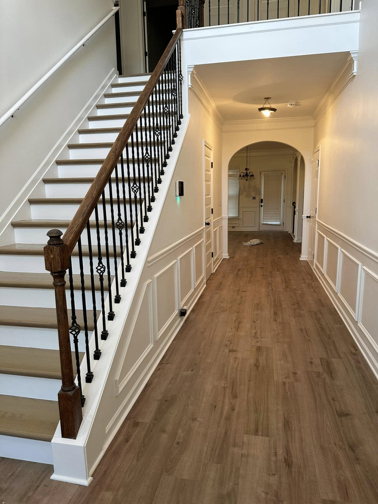 Foyer with refinished staircase and new hardwood-style flooring
