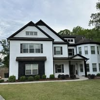 White two-story home with black accents and landscaped yard
