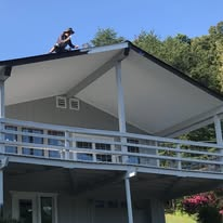 Crew painting a covered deck roof on a hillside home