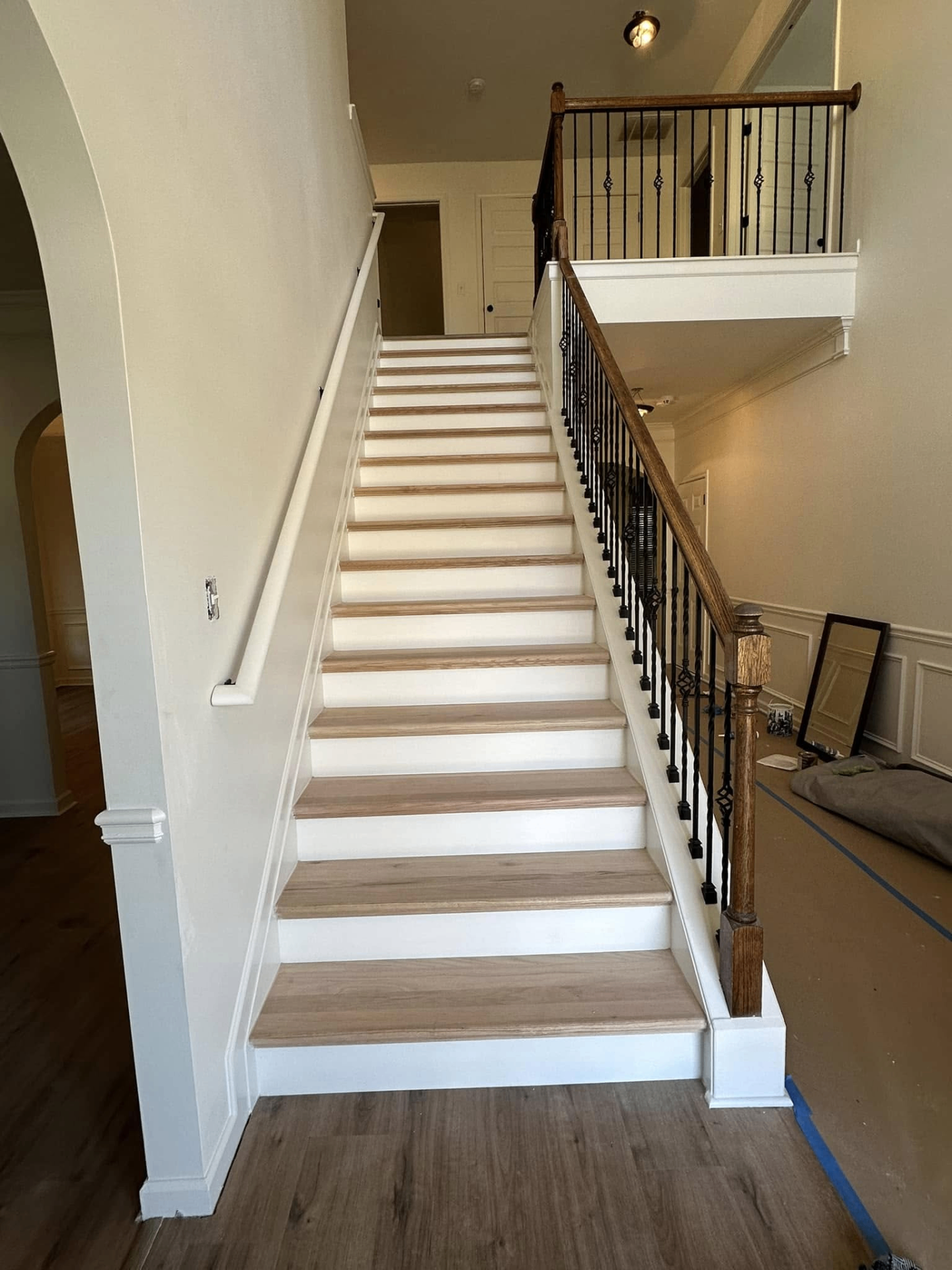 Staircase with white risers, wood treads, and iron balusters